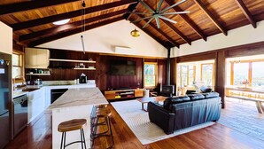 Un espacio habitable amplio con chimenea, un ventanal grande y techo de madera.