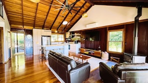 A spacious living area with a wooden ceiling, a fireplace, a kitchen with a bar, and large windows. - CHRISTOPHERS COTTAGE - the quintessential mountains retreat - SPECIALS ON NOW ! (Bilpin)