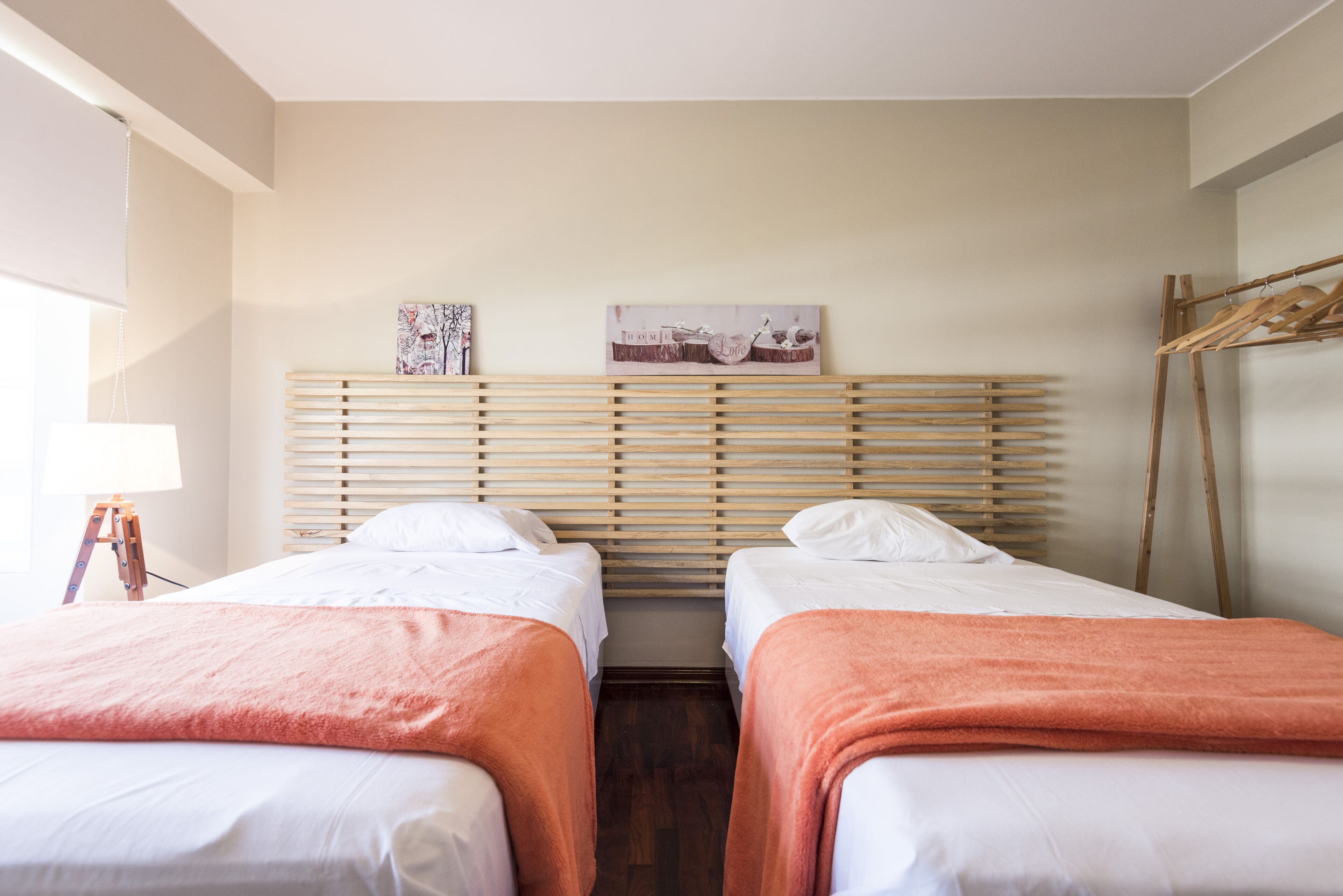 A hotel room with two beds, wooden headboards, a wooden floor, and a painting on the wall.