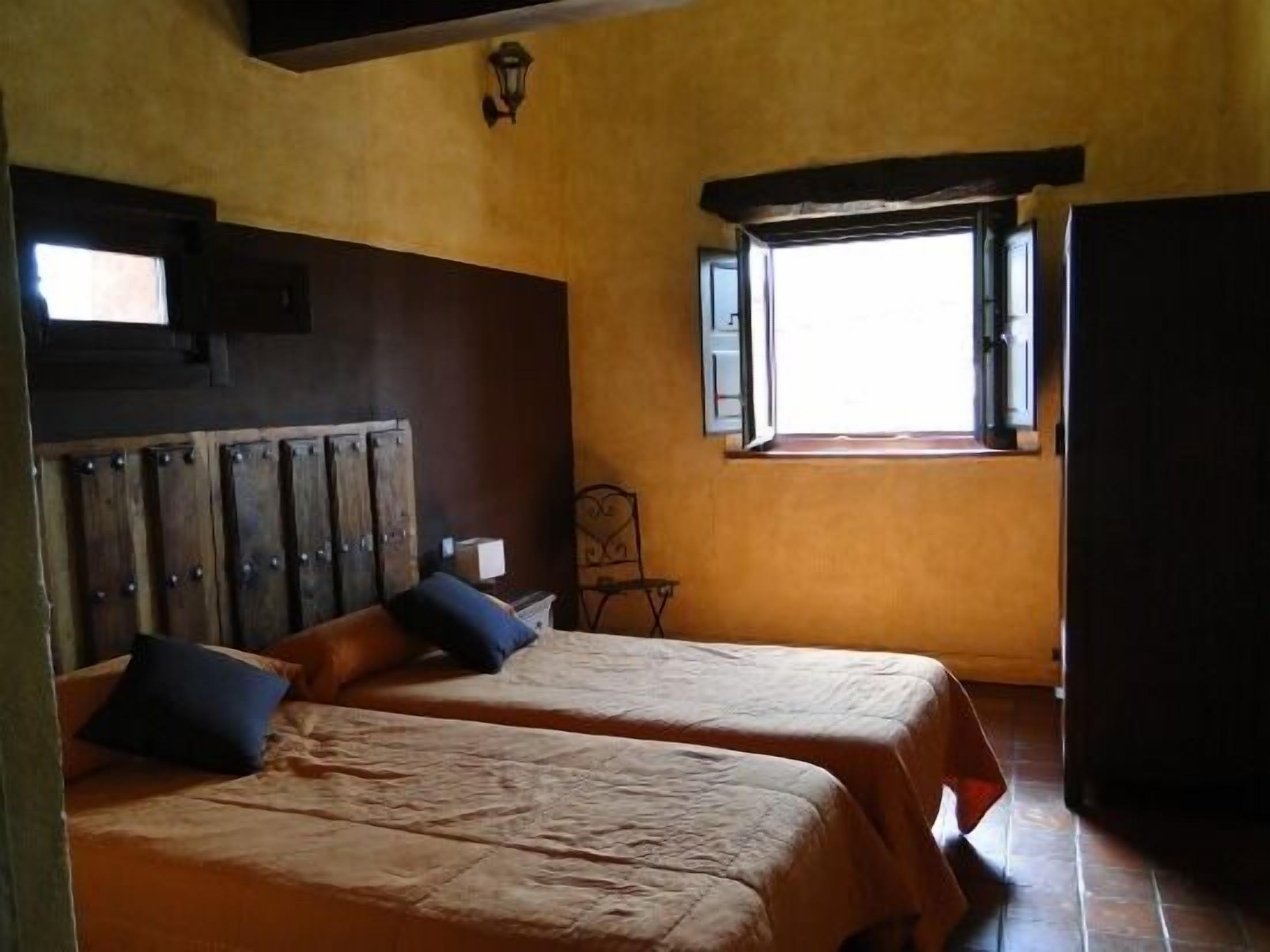 Une chambre avec deux lits, une armoire en bois, une fenêtre donnant sur un beau paysage et une petite table.