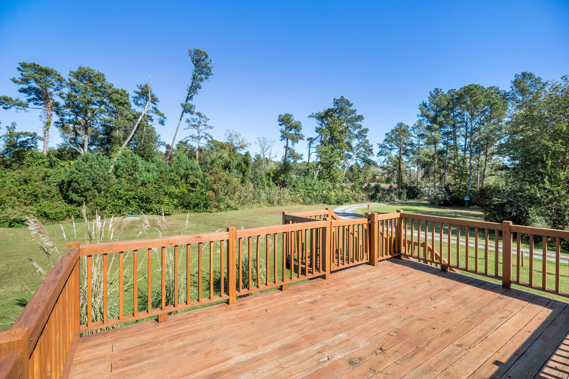 A wooden deck with a view of a golf course and surrounding trees.