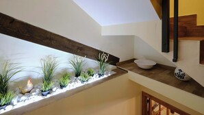 Un intérieur moderne avec une poutre en bois, un mur blanc et un petit lavabo blanc posé sur un comptoir.