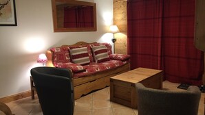 A cozy living room with a wooden sofa, two side chairs, a small wooden table, and a red plaid curtain. - Spacious 3 Bedroom Apartment Right on the Slopes (Les Esserts, Morillon)