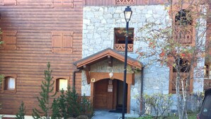 A building with a stone facade and wooden upper levels, a covered entrance, and a pathway leading to the entrance. - Spacious 3 Bedroom Apartment Right on the Slopes (Les Esserts, Morillon)