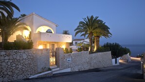 A coastal building with stone walls, arched windows, and palm trees. - Wonderful luxury villa in 1st line of the sea in Moraira with private pool. (Teulada / Moraira)