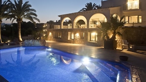 A pool area with a stone building in the background, featuring arched windows and balconies. - Wonderful luxury villa in 1st line of the sea in Moraira with private pool. (Teulada / Moraira)