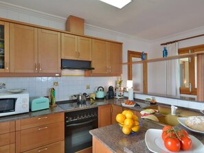 A kitchen with wooden cabinets, a microwave, a toaster, a kettle, and a sink.