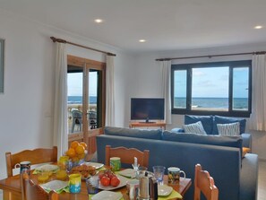 A living room with a sofa, a television, and a dining area with a table set for breakfast.