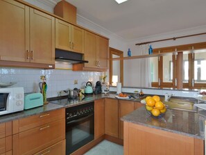 A kitchen with wooden cabinets, a microwave, a stove, and a bowl of oranges on the counter.