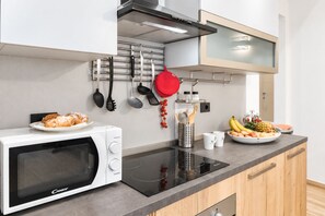 A modern kitchen with a built-in microwave, an induction cooktop, and a stainless steel range hood. - I FRAGOLI A SANTA CROCE (Firenze)