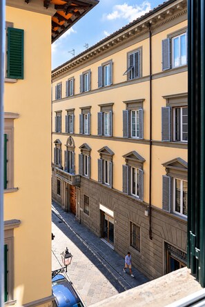 A street view of a building with multiple windows and a person walking on the sidewalk. - I FRAGOLI A SANTA CROCE (Firenze)