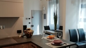A modern kitchen with a wooden island, pendant lights, and a dining area with chairs and a table set for two. - I FRAGOLI A SANTA CROCE (Firenze)