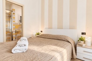 A modern bedroom with a large bed, a glass shower enclosure, and a bedside table with a lamp and a plant. - I FRAGOLI A SANTA CROCE (Firenze)