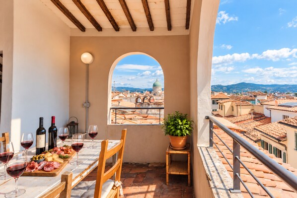 A balcony with a table set for a meal, a bottle of wine, and a potted plant. - I FRAGOLI A SANTA CROCE (Firenze)