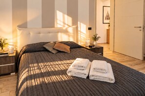 A bedroom with a large bed, two bedside tables, a nightstand, a wall-mounted lamp, and a framed picture on the wall. - I FRAGOLI A SANTA CROCE (Firenze)