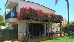 A two-story house with a covered patio area, outdoor seating, and a well-maintained lawn.