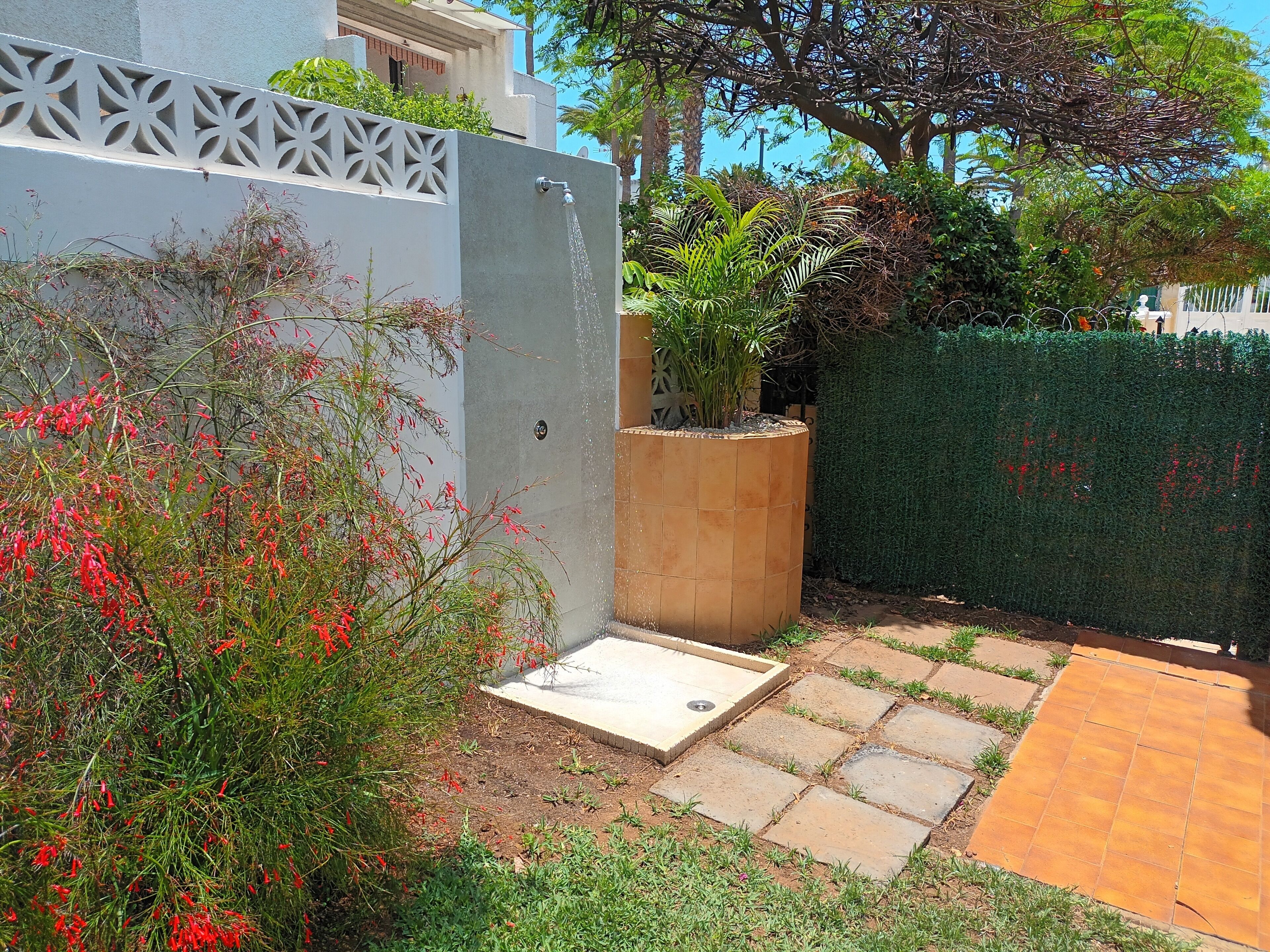 Un jardin agrémenté d’un élément aquatique, d’un bac à fleurs et d’un chemin pavé.