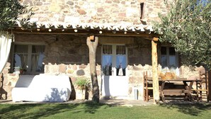 A stone building with a covered patio, a wooden table, and potted plants. - DomusAntiga three-room apartment 10 minutes from the most beautiful beaches of the coast!Wifi (San Giovanni Suergiu)