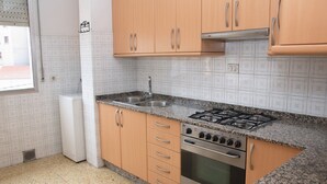 A kitchen with wooden cabinets, a stainless steel sink, a gas stove, and a built-in oven.