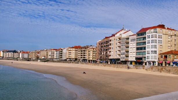 A coastal hotel with multiple floors, balconies, and a beachside location.