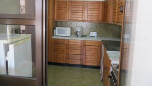 A small kitchen with wooden cabinets, a microwave, a coffee maker, and a toaster. - Magnificently located apartment with sea view (Lagos)
