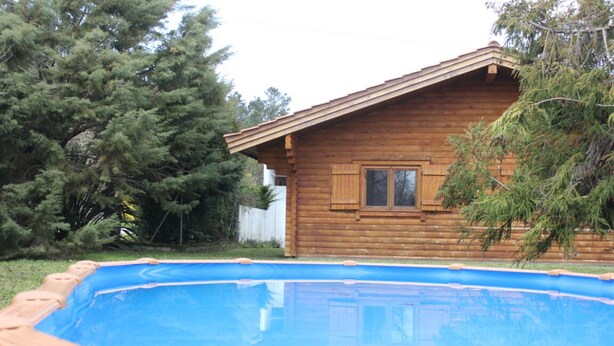 Une cabane en bois avec une piscine devant.