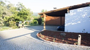 Une allée pavée menant à un bâtiment doté d’un toit en bois et d’un mur blanc.