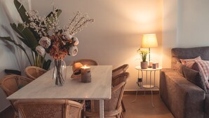 A cozy living room with a dining table, wicker chairs, a lit candle, a lamp, and a couch. - Apartment La Invencible Terreros in 1st line of beach (San Juan de los Terreros)