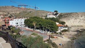Un poble costaner amb un edifici blanc destacat, una zona de platja i una obra en curs.