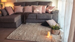 A cozy living room with a grey sofa, multiple cushions, a fluffy rug, and a lit candle. - Apartment La Invencible Terreros in 1st line of beach (San Juan de los Terreros)