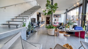 A modern living room with a staircase, a large plant, and a seating area with a coffee table. - LAST MINUTE -  Design villa, climatized pool, sea views 6 pers. (Tijoco Bajo)