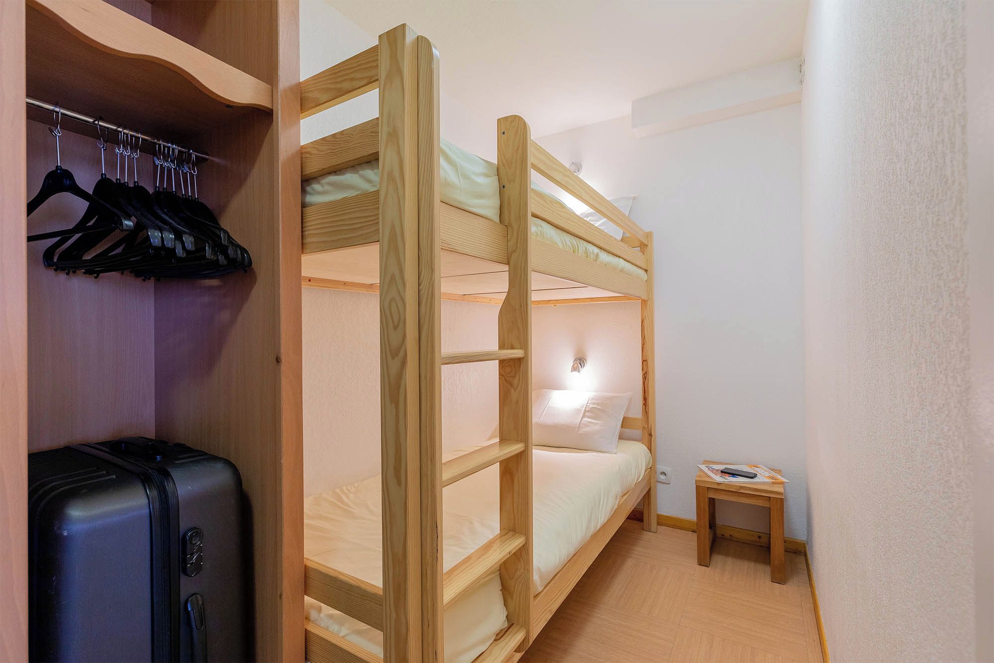 Habitación con literas, una maleta y una mesita pequeña.