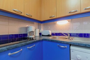 A kitchen with wooden cabinets, a built-in toaster, a coffee maker, and a dishwasher.
