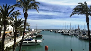 Un puerto deportivo con barcos amarrados, palmeras y un edificio con un letrero.