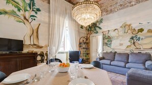 Un comedor con una mesa dispuesta para cuatro, una araña y un mural de árboles en la pared.