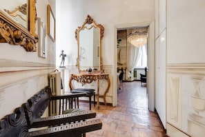 Un amplio pasillo con muebles ornamentados, un espejo grande y una araña.