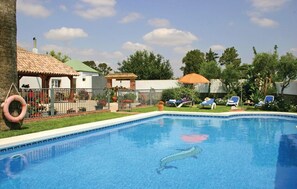 A swimming pool with lounge chairs, a lifebuoy, and a fenced garden area.