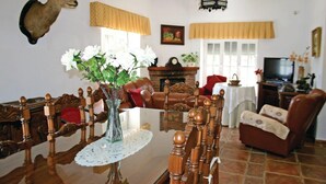 A living room with a dining table, chairs, a fireplace, a television, and a mounted deer head.