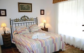 A neatly made bed with striped bedding, two bedside lamps, and a framed picture above the headboard.