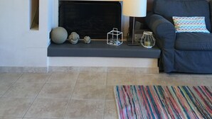 A living room with a sofa, a fireplace, decorative hats on the wall, and a framed map. - Seafront apartment ΙΙ in Kiveri, near Nafplion. (kiveri)