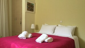 A hotel room with a bed, white pillows, a red bedspread, and two rolled towels on the bed. - Seafront apartment ΙΙ in Kiveri, near Nafplion. (kiveri)