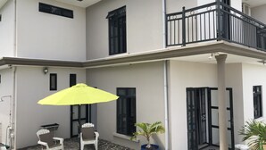 Ein zweistöckiges Gebäude mit einem Balkon, einem gelben Sonnenschirm und einem Blumentopf.