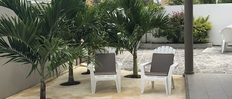 A patio area with white chairs and a small pool.