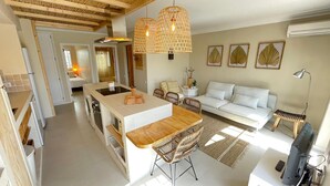 Een moderne keuken met een centraal eiland, een eethoek met een witte bank, en een woonkamer met een witte zithoek.