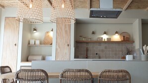 Een moderne keuken met houten kastjes, een betegelde spatwand en een centraal eiland met barstoelen.