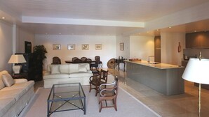 A modern living room with a sofa, chairs, a coffee table, and a kitchen area with a bar.