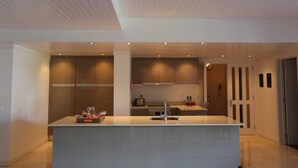 A modern kitchen with a central island, recessed lighting, and wooden cabinets.