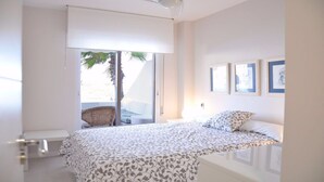 A bedroom with a bed, a chair, a balcony with a view of the beach, and framed pictures on the wall. - Beautiful house in La Manga The pedruchillo. First line beach garage and pool (San Javier)
