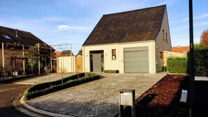 Een gebouw met twee verdiepingen, een pannendak, een garage en een geplaveid oprit.