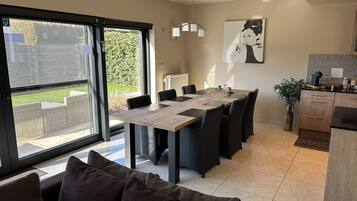 A modern kitchen with a dining area, large windows, and a view of the garden.